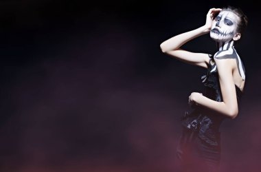 Ölüler Günü ve Cadılar Bayramı. Siyah arka planda balkabağı kafatası makyajı olan zarif bir kadın. Boşluğu kopyala.