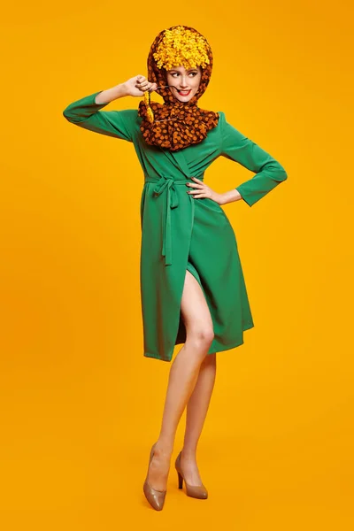 Modern pin-up style. High fashion pretty woman model posing in fashionable elegant clothes and with mimosa flowers on her head and glasses. Bright saturated colors. Copy space.