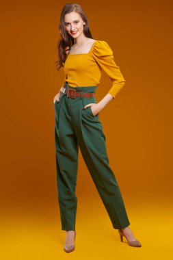 Renkli giysiler içinde kameraya gülümseyen güzel, modern bir kızın tam boy portresi. Moda fotoğrafı..