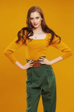 Kendine güvenen renkli elbiseli modern kız kameraya gülümsüyor. Turuncu arka planda hippi kız portresi. Moda fotoğrafı..