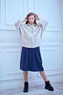 Açık renk ceketli, uzun etekli, beyaz klasik bir iç mekanda poz veren güzel sarışın bir kızın tam boy portresi. Bahar ve sonbahar giysileri moda..