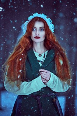 Noel Masalı. Uzun kızıl saçlı, ortaçağ kıyafetleri giyen güzel bir genç kadının portresi karlı bir ormanda yürüyor. Orta Çağ 'ın erken dönemlerinin tarihi yeniden yapılandırması.. 