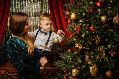 Aile Noel 'i ve yeni yıl. Mutlu anne küçük oğluna güzel bir Noel ağacı gösterir..
