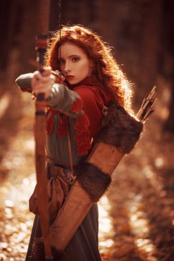 Orta Çağ 'ın güzel kızıl saçlı okçusu bir ormanda duruyor. Hayal dünyası..
