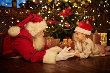 Kibar yaşlı Noel Baba evde Noel ağacının yanında küçük bir kızla oynuyor. Mutlu Noeller ve mutlu yıllar.!