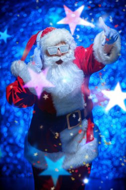 Kar ve kulaklıkla kaplı gözlüklü Noel Baba. Noel şarkıları ve müzik. Arka planda disko ışıkları. 