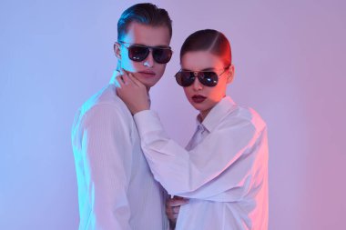 Beyaz gömlekli ve modern güneş gözlüklü bir mankenin portresi. Gözlük modası. Stüdyo çekimi.