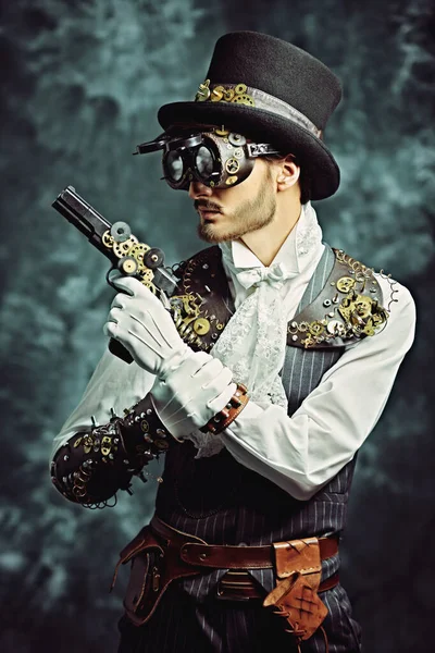 Portrait of a courageous victorian steampunk man standing with a gun on a grunge background. Fantasy world, adventures.