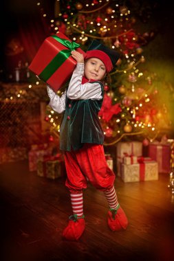 Şirin gülümseyen elf kızı çocuklar için bir hediye tutuyor. Noel Baba 'nın Evi.