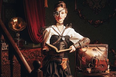 Güzel steampunk kadın bilim adamı laboratuarında duruyor ve bir kitap okuyor. Viktorya döneminden kalma iç mimari. 