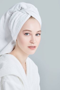 Beyaz bornozlu güzel bir genç kadın portresi ve duş aldıktan sonra saçının etrafına bir havlu. Güzellik, vücut bakımı, kaplıca.