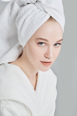 Güzellik, vücut bakımı, spa. Beyaz bornozlu güzel bir genç kadın portresi ve duş aldıktan sonra saçının etrafına bir havlu.. 