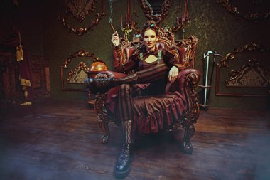 Bilim kurgu, maceralar. Güzel bir steampunk kadını, Victoria tarzı iç mimarisi olan bir odada bir koltukta oturur.. 