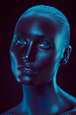 Vücut sanatı projesi. Siyah tenli ve yüzünde parlak bir parıltı olan mükemmel bir kadının yakın plan güzel portresi. Makyaj ve makyaj malzemeleri. Siyah arkaplan.