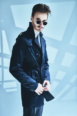 Modern bir iş adamının portresi. Zarif siyah takım elbiseli, beyaz gömlekli ve gölgeli gri bir arka planda poz veren modern stil sahibi bir adam. Erkek modası.