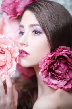 Zarif mor eflatun makyajlı ve saçlarında şakayık çiçekleri olan muhteşem bir manken. Moda ve çiçekler. Makyaj, saç stili. Parfüm konsepti.
