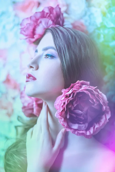 Beautiful young woman with gentle purple lilac make-up and peony flowers in her hair. Fashion and flowers. Make-up, hairstyle. Perfume concept.