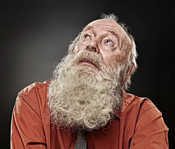 Old age concept. Portrait of an old man with white beard looking up expectantly. Black background. Religion and belief in God.