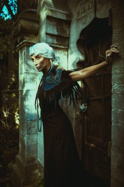 Fantezi Dünyası. Güzel gri saçlı ve zengin siyah elbiseli aristokrat bir dul kadın mezarlıktaki bir mezarlıkta görkemli ve heybetli duruyor. Kara Dul. Cadılar Bayramı.