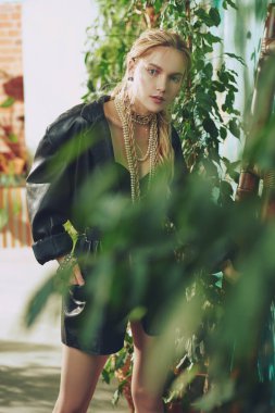 Şık genç kadın modeller serada siyah deri ceket, altın ve inci takılarla poz verirler. Moda ve mücevher. 