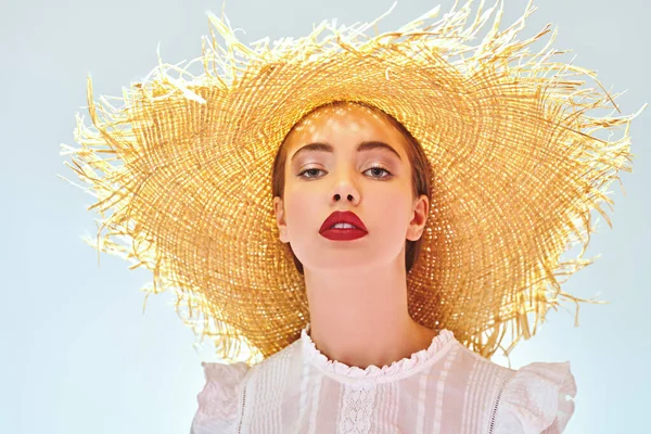 Summer style. Portrait of a beautiful elegant girl in a white blouse and straw hat. Beauty and cosmetics.