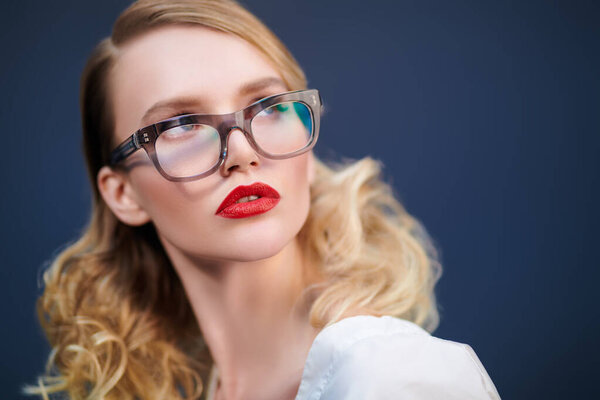 Бизнес стиль. Портрет модной блондинки в элегантных очках на сером фоне. Оптика, очки. Копирование пространства.
