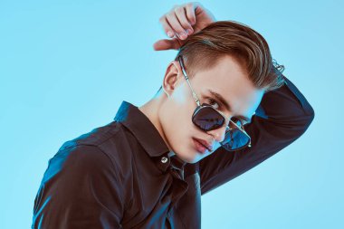 Erkek aksesuarları, optikler. Modern güneş gözlüklü yakışıklı genç adam. Stüdyo resmi. 