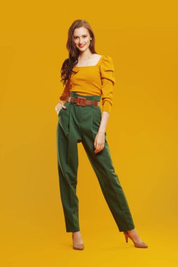 Renkli giysiler içinde kameraya gülümseyen güzel, modern bir kızın tam boy portresi. Moda fotoğrafı..