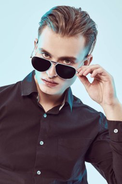 Modern güneş gözlüklü yakışıklı genç adam. Erkek aksesuarları, optikler. Stüdyo resmi. 