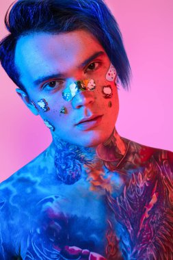 Portrait of a modern guy with bright dyed hair, stickers and decorative adhesive plaster on the face and colorful tattoo on his body. Anime style. 