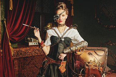 Steampunk dünyası. Çarpıcı steampunk kadın bilim adamı laboratuarında duruyor ve sigara içiyor. Viktorya döneminden kalma iç mimari. 