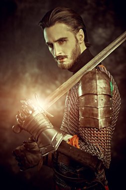 Medieval knight with a sword and armour on a black background. clipart