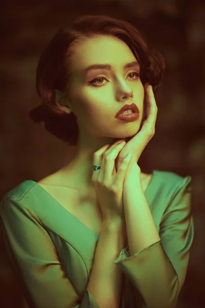 Hair and makeup in the style of the 20s. Beautiful sophisticated girl in an elegant dress stands against the background of an old vintage wall. Art fashion.