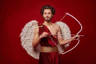 Sevgililer Günü konsepti. Aşk Tanrısı 'nın portresi - Kırmızı arka planda yay ve okla Aşk Tanrısı. 