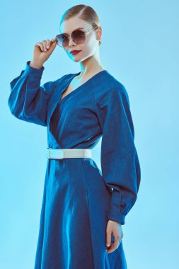 Yaz stili. Mavi elbiseli ve şık güneş gözlüklü güzel bir kadının portresi. Gözlük modası. 
