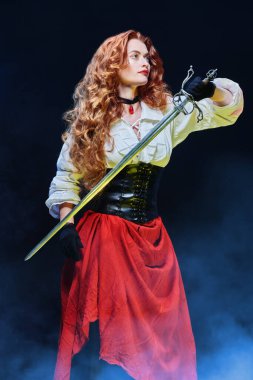 16.-17. yüzyılın tarihi yeniden yapılandırması. Güzel kızıl saçlı bir kadının portresi ve savaş çadırı (rapier). Bir macera romanının kahramanı.. 