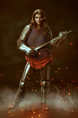 Orta Çağ tarihi. Siyah arka planda zırhlı güzel bir ortaçağ kadın şövalyesinin tam boy portresi.