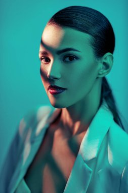 Zarif esmer kadın renkli akuamarin ışıklarıyla poz veriyor. Güzellik portresi. Makyaj ve kozmetik.