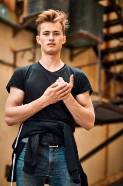 Şehrin eski semtinde, günlük giysiler içindeki yakışıklı genç adam sokakta duruyor. Kentsel grunge tarzı. 