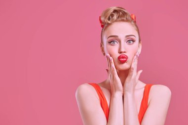 Sevgililer Günü. Pembe arka planda dolgun dudakları olan çarpıcı sarışın bir afiş kızı portresi. Makyaj ve saç stili. Boşluğu kopyala.