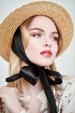 Hasır şapkalı güzel sarışın kız ve beyaz arka planda bir yaz bluzu. Pembe renkli açık renk makyaj. Bahar ve yaz güzelliği. Moda.. 