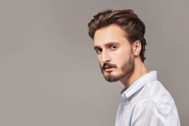 Stüdyoda beyaz gömlekli yakışıklı bir esmer adam portresi. Erkek güzelliği ve saç stili. Boşluğu kopyala.