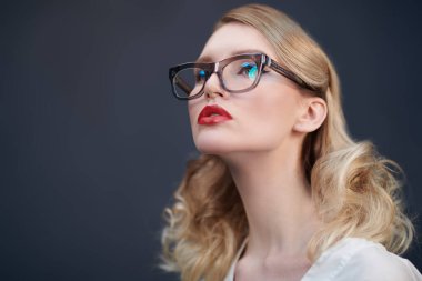 İş stili. Zarif gözlüklü şık sarışın bir kadının stüdyo portresi. Optik, gözlük. Boşluğu kopyala.
