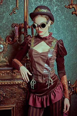 Viktorya döneminden kalma iç mimarisi olan bir odada duran fütürist gözlüklü güzel bir steampunk bayanın portresi. Steampunk dünyası. 