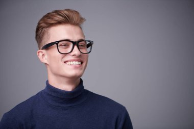 Sarı saçlı ve kameraya gülümseyen yakışıklı bir gencin portresi. Erkek güzeli. Erkekler için optik.