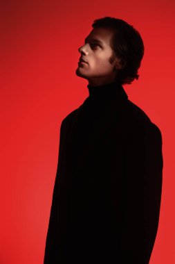 Zarif elbiseli yakışıklı genç adam kırmızı ışıkta stüdyoya bakıyor. Erkek tarzı. Profilde portre.