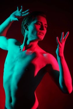 Kırmızı ve yeşil ışıkta çıplak bedenle poz veren yakışıklı bir genç adamın portresi. İnsanın güzelliği ve sağlığı. Resim..