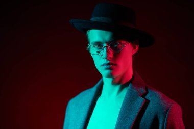 Çıplak bir gövde, şapka ve şık gözlüklerle poz veren yakışıklı bir genç adamın portresi. Erkek modası. Erkekler için optik.