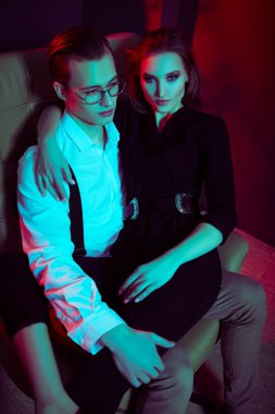 Yakışıklı genç adam sevgilisine sarılıyor, lüks bir dairede bir koltukta oturuyor, flört ediyor. Göz kamaştırıcı bir yaşam tarzı. Moda fotoğrafı..