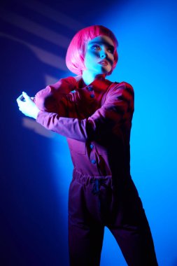 Parlak makyajlı ve gölgelerde poz veren pembe saçlı muhteşem bir genç kadın portresi. Makyaj malzemeleri ve saç stili. Moda güzelliği trendleri.  